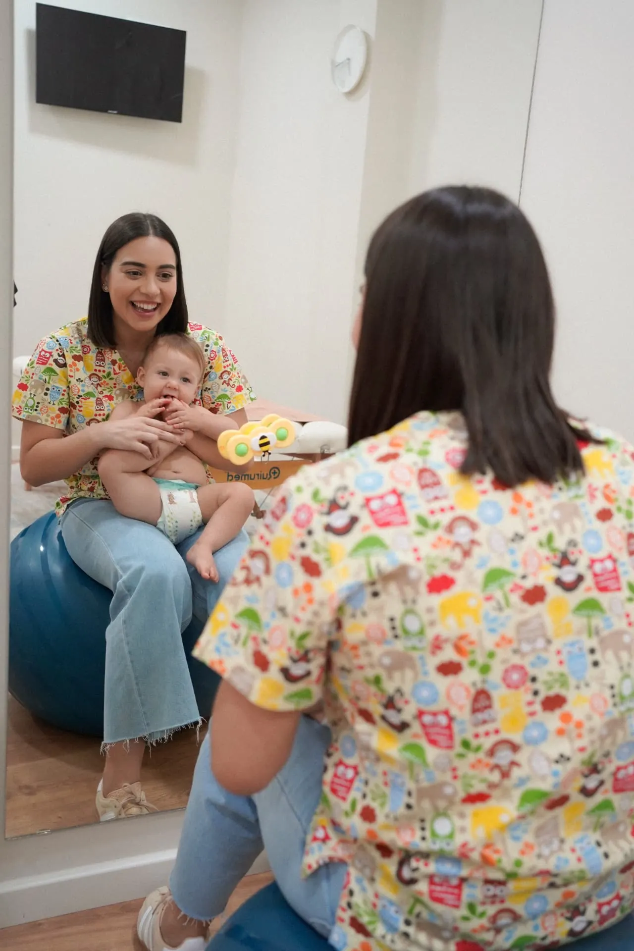 Consulta de osteopatia com bebé ao colo em frente ao espelho